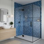 A modern shower with blue glass mosaic tiles, black fixtures, and a clear glass door in a contemporary bathroom.