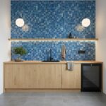 Blue glass tile backsplash with mosaic pattern behind kitchen sink and countertop.