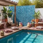 Vibrant outdoor pool area featuring a glass mosaic tile backsplash, cozy seating, and lush plants for a relaxing ambiance.