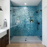 Blue glass tile shower with mosaic accents and built-in shelves, creating a modern and luxurious bathroom feature.
