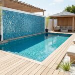 A stunning outdoor pool with a glass mosaic tile wall, perfect for modern backyard design and poolside relaxation.