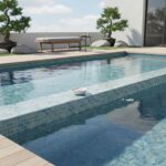 A swimming pool featuring a glass mosaic tile backsplash, surrounded by a sleek deck and minimalist outdoor furniture, with t.