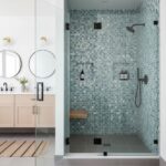 Modern glass tile shower featuring blue mosaic tiles, built-in shelves, and a sleek black showerhead for a stylish bathroom u.