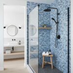 Blue glass mosaic tile backsplash in contemporary bathroom shower with black fixtures.