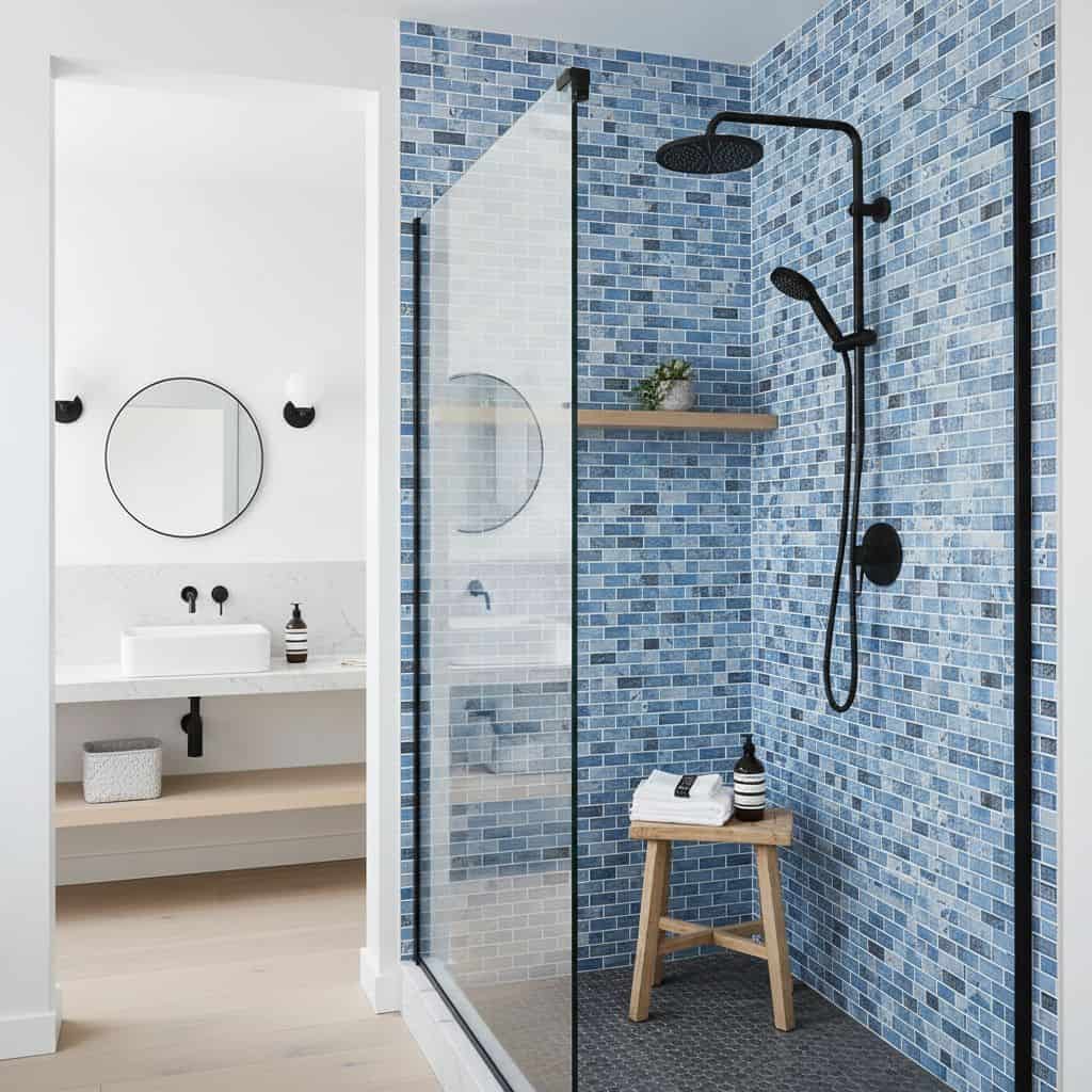 Blue glass mosaic tile backsplash in contemporary bathroom shower with black fixtures.