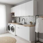 Modern laundry room with peel and stick wall tile, white cabinets, and washer-dryer setup.
