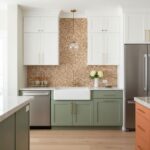 A modern kitchen featuring a peel and stick tile backsplash behind the sink, with white upper cabinets and green lower cabine.