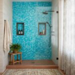 Beautiful shower wall decorated with mother of pearl shell tiles in shades of blue, featuring built-in niches for toiletries.