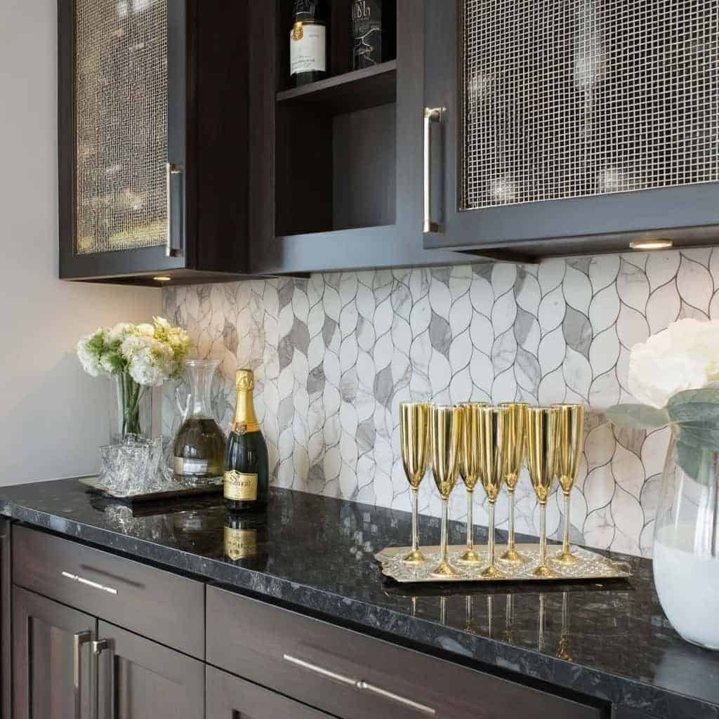A modern kitchen featuring a peel and stick tile backsplash with a sleek, black countertop and elegant decor.