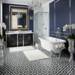 Navy bathroom with geometric black and white tile flooring, white bathtub, and elegant decor.