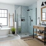A stylish bathroom featuring a glass tile backsplash in the shower area, complemented by a freestanding bathtub and wooden ac.