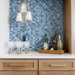 Blue glass tile backsplash with barware and bottles for home decor.