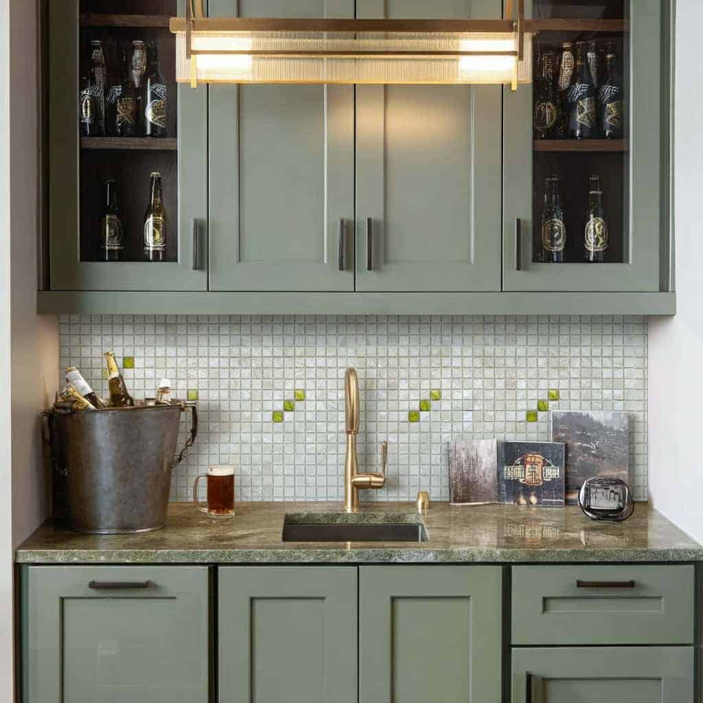 Seashell tile backsplash with mother of pearl accents in a contemporary kitchen, featuring a gold faucet, glass bottles, and.