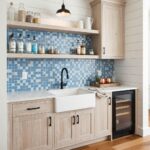 Blue glass tile backsplash in modern kitchen with open shelving and farmhouse sink.