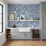 Blue glass tile backsplash in a contemporary kitchen with white cabinets, gold fixtures, and decorative accessories.