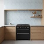 Modern kitchen with light-colored glass mosaic tile backsplash and wooden cabinets, featuring a black stove and decorative sh.