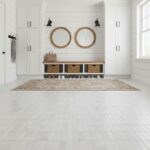 Bright white ceramic tiles with a smooth finish, complemented by a wooden storage bench and round wall mirrors.