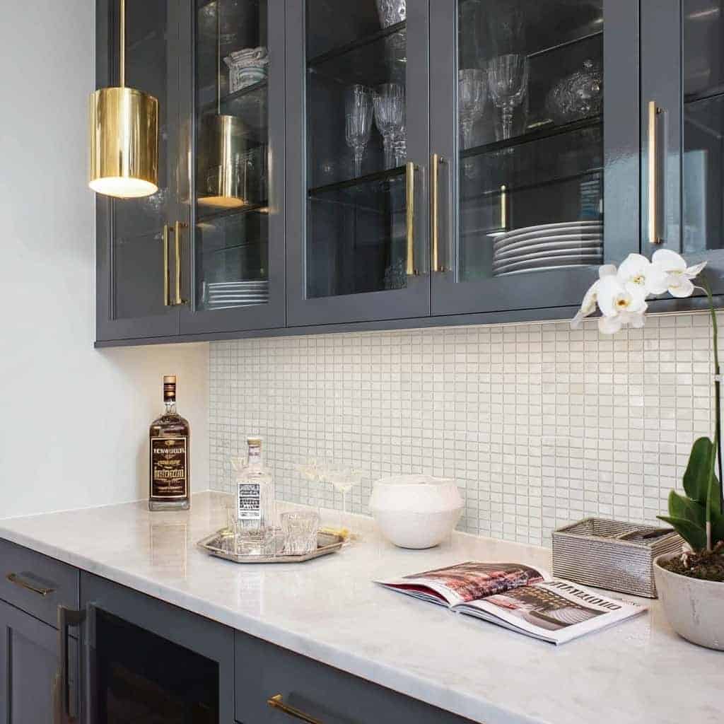 Modern kitchen with mother of pearl shell tile backsplash and stylish blue cabinetry.