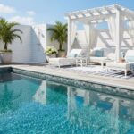 Bright poolside lounge with white cabana, tropical palms, and seating area.