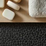 Black pebble tile with smooth, rounded texture and matte finish, ideal for bathroom or spa settings.