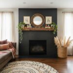 Black brick fireplace with wooden mantel and round mirror, flanked by framed botanical prints and lush green plants, in a coz.