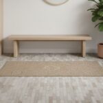 Beige textured tile floor with a matte finish, in a modern interior setting with a plant and bench.