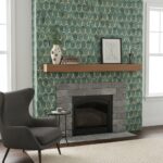 Teal and gold patterned wallpaper with gray stone fireplace and wooden mantel.