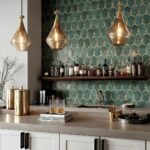 Elegant gold pendant lights with textured finish hanging above a kitchen counter with a dark patterned tile backsplash.