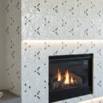 White and black mosaic tiles with a textured surface surrounding a sleek black fireplace.