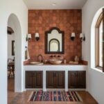 Rust-colored terracotta tile wall with textured surface behind bathroom vanity.