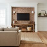 Bright, textured mosaic tile wall with warm earthy tones behind TV.