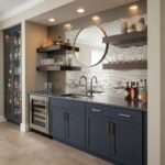 Navy blue cabinet with black countertop, glassware, and round mirror in contemporary kitchen setting.