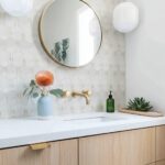 Beige hexagon tiles with a smooth texture, complemented by a round mirror and simple bathroom accessories.