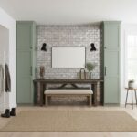 A textured gray brick wall with black wall sconces, flanked by sage green cabinets, and a wooden console table with decor in.