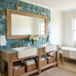 Blue mosaic tile wall with textured surface behind double white farmhouse sinks.