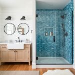 Blue mosaic tile shower with textured surface and glass door.