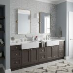 Double sink vanity with gray cabinets, white countertops, and gold hardware in a modern bathroom.