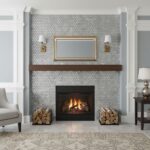 Hexagon tile in light gray with a matte finish, surrounding a black fireplace. Elegant, contemporary design with a wooden man.