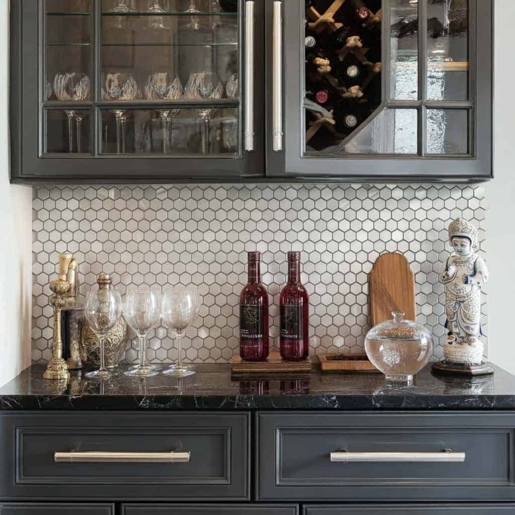 Elegant black marble kitchen countertop with glassware, wine bottles, and decorative figurine.