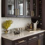 Dark wood cabinets with gold handles, white marble surface, and glassware display.