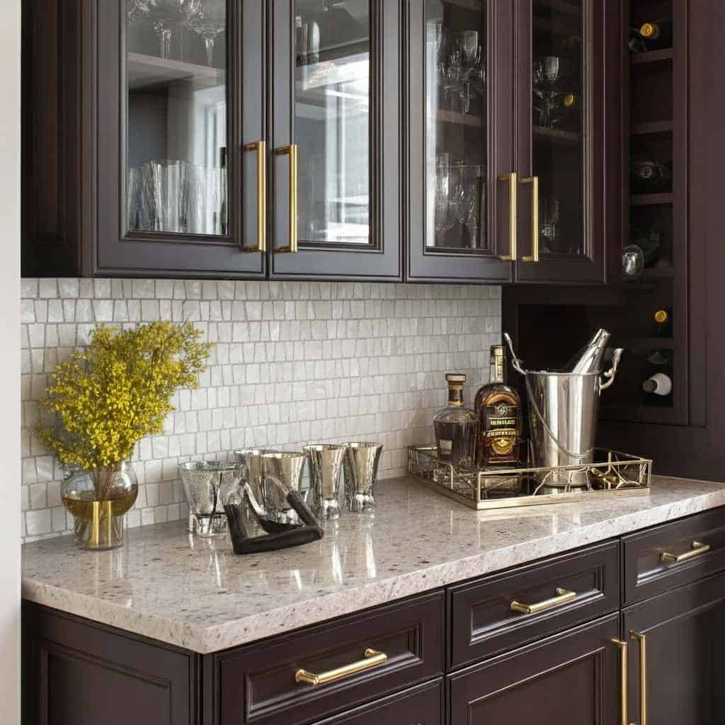 Dark wood cabinets with gold handles, white marble surface, and glassware display.