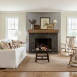 Elegant living room with a white sofa, wooden accents, and a cozy fireplace, featuring neutral tones and natural light.