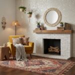 A warm living room featuring a white brick fireplace, a yellow armchair with patterned cushions, hanging plants, and a vintag.