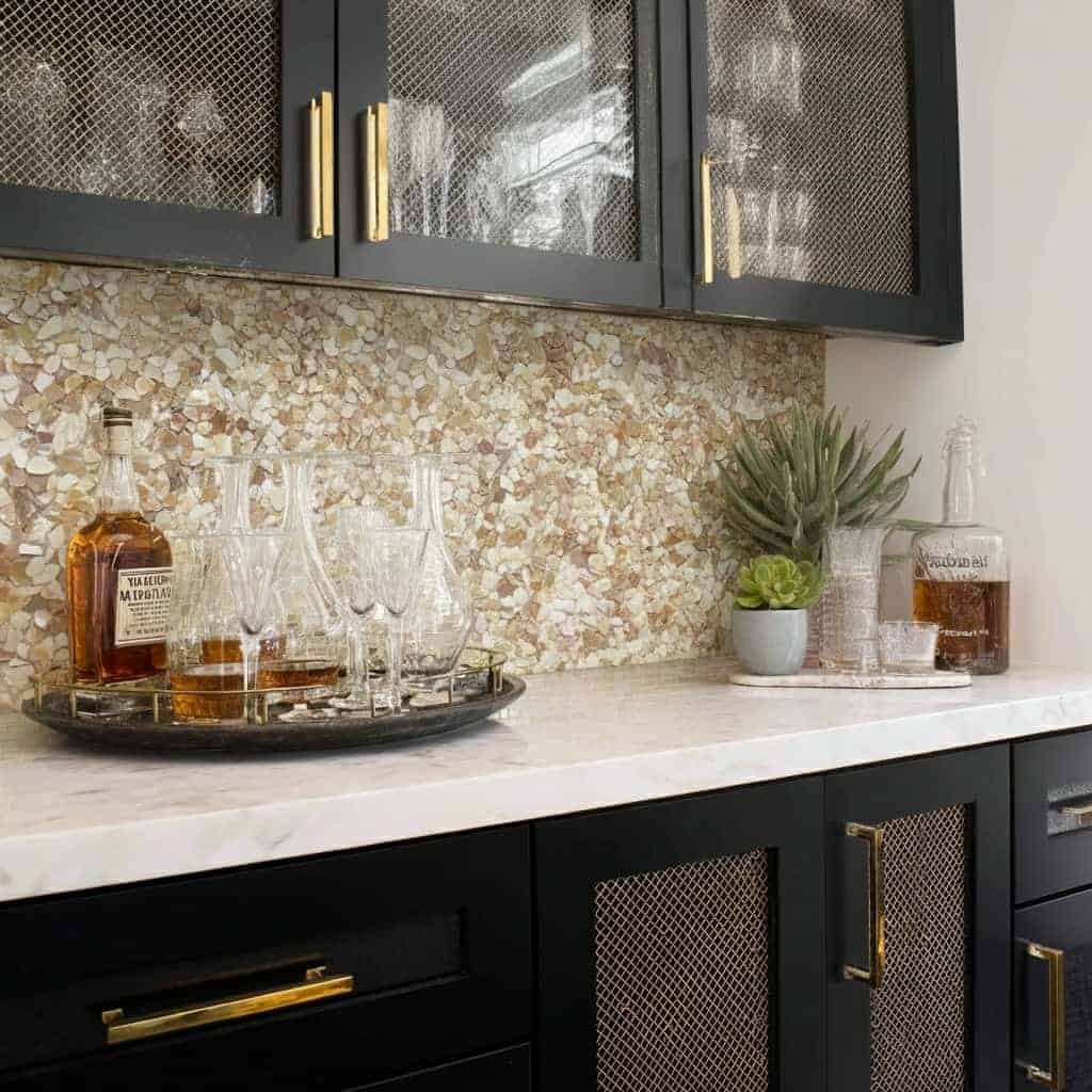 Black cabinets with gold accents and a textured backsplash.
