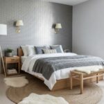 A cozy bedroom featuring a textured gray brick wall, white bedding, and wooden furniture, creating a calm and inviting atmosp.