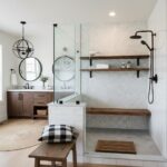 Bright bathroom with white tiles, black fixtures, and wooden shelves, featuring a walk-in shower with a glass partition and a.