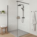 White mosaic tile with subtle beige accents, textured surface, modern black shower fixtures.