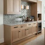 Bright wood kitchen cabinets with black handles and a mosaic tile backsplash.