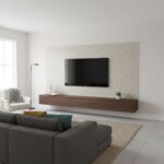 A textured, light-colored tile wall behind a mounted flat-screen TV in a contemporary living room.