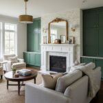 Bright living room featuring green cabinetry, white fireplace, and natural light from large windows. Elegant and inviting hom.
